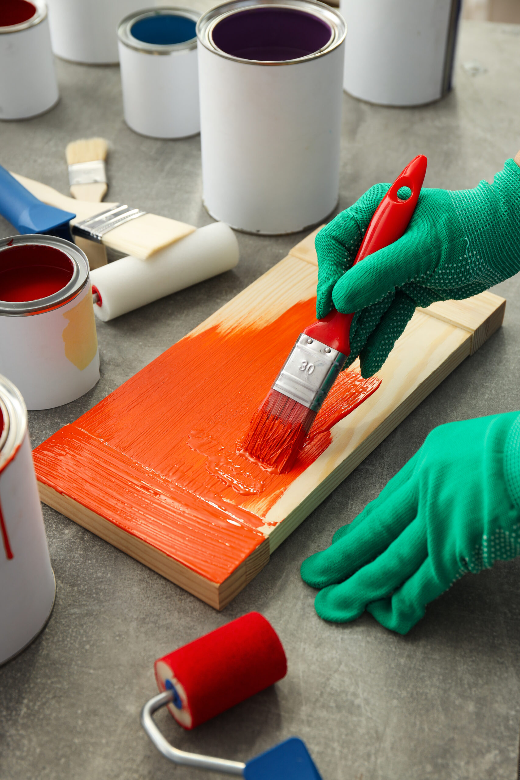 Hand in glove paints board with brush, close up